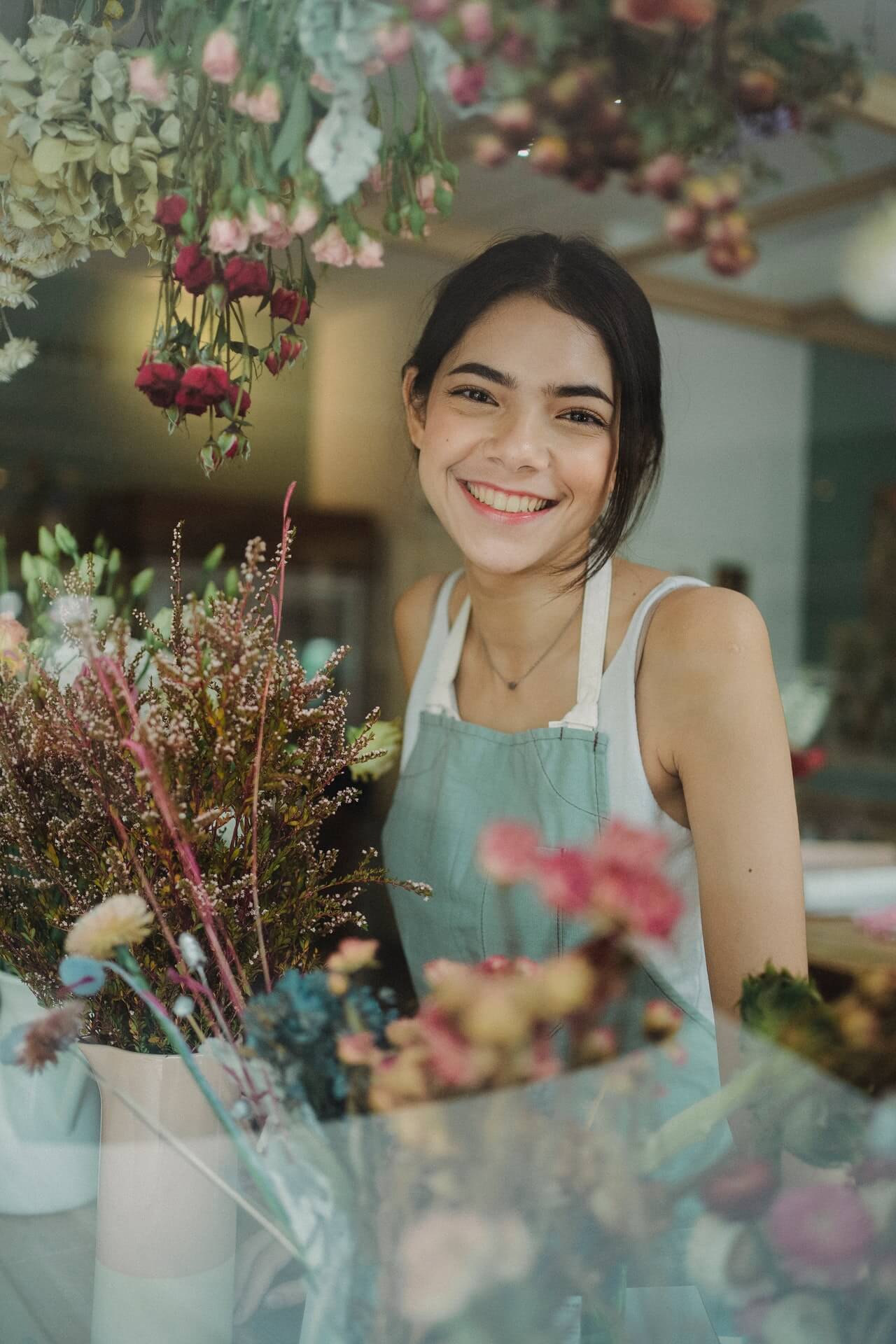Glimlachende bloemiste in haar winkel.